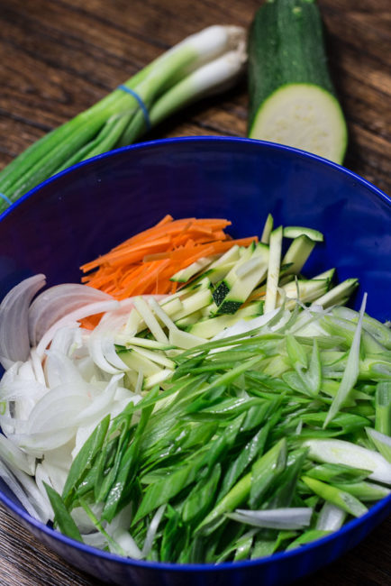 thinly sliced green onion, onion, zucchini ,and carrot in a large bowl