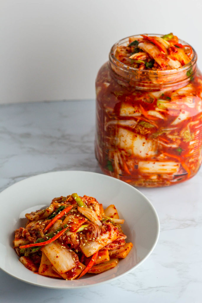 Vegan Kimchi in a big jar and plateful of freshly made kimchi in front