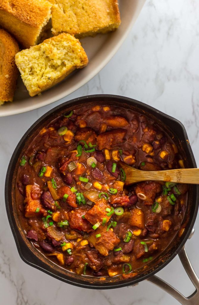 Overhead shot of pot of chili with corn bread on the side
