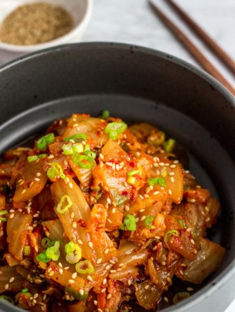 Close up picture of stir fried kimchi in a black bowl