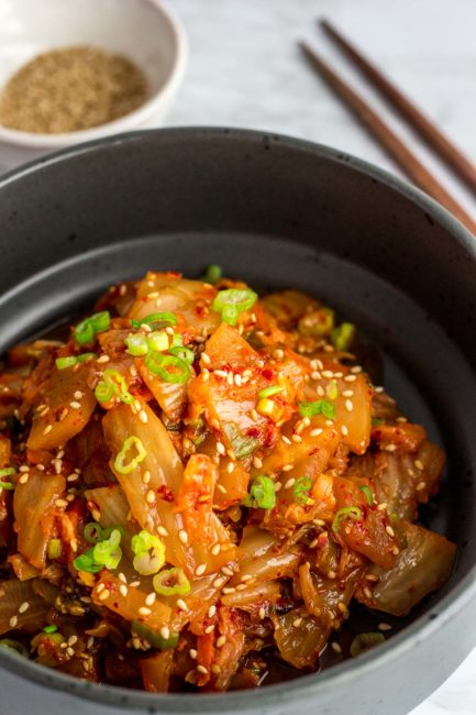 Close up picture of stir fried kimchi in a black bowl