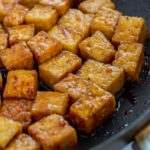 Close up shot of teriyaki tofu in the pan being simmered in the sauce