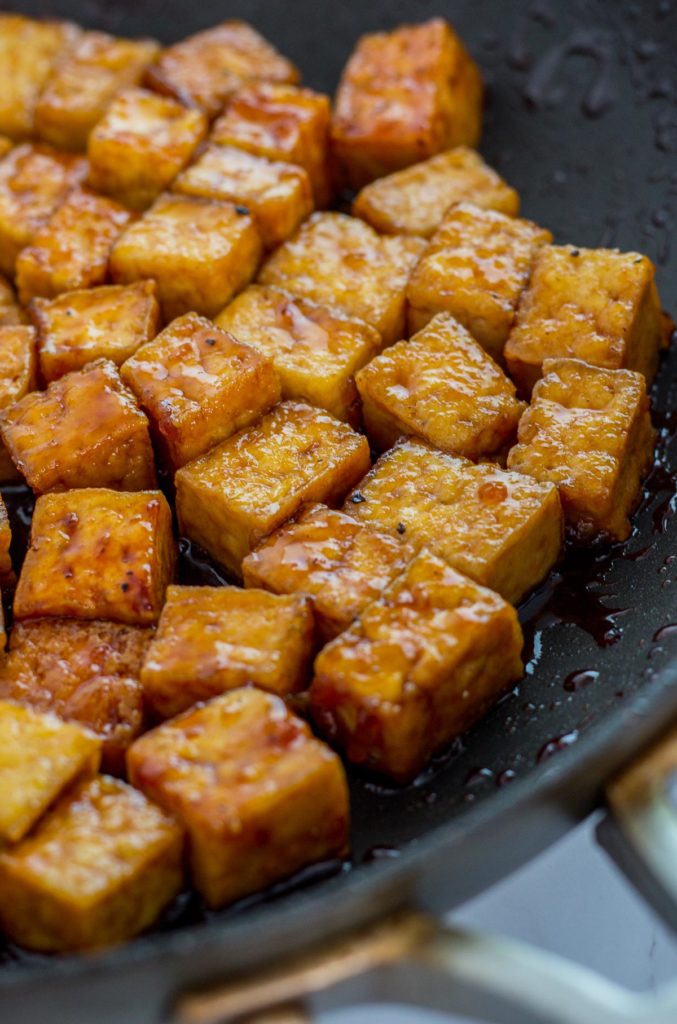 Close up shot of teriyaki tofu in the pan being simmered in the sauce