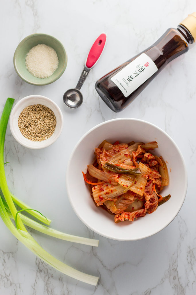 ingredients for stir fried kimchi - fermented kimchi, green onion, sesame seeds, sesame oil, and sugar