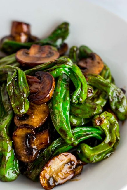 Close up shot of stir fried shishito pepper and mushroom slices