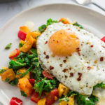 winter squash kale hash on a white plate with fried egg on top