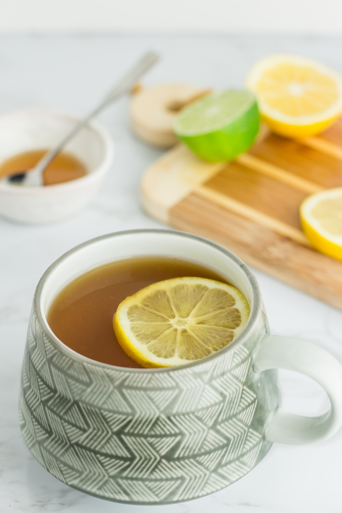 photo of tea with lemon slice on top and have lemon and honey in the background