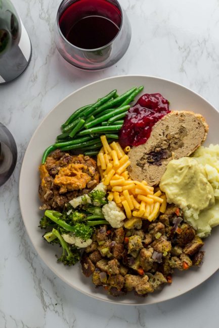 Vegetarian thanksgiving dinner plate - green bean, cranberry sauce, vegan turkey, mac and cheese, mashed potato, stuffing, and roasted broccoli and cauliflower