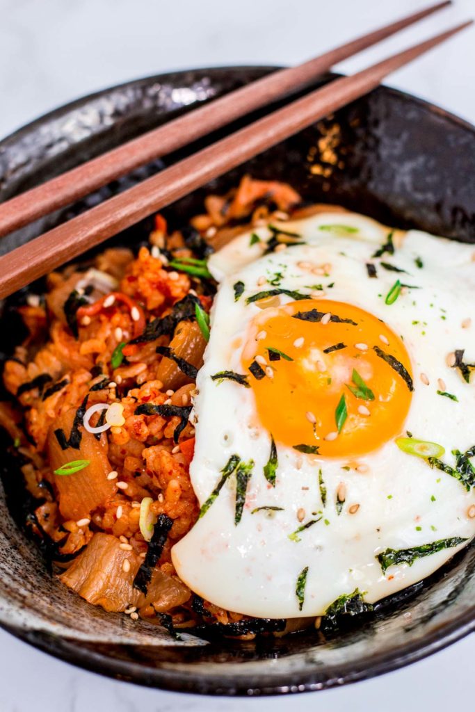 another picture of bowl full of kimchi fried rice with fried egg and seaweed paper strips and green onion as garnish