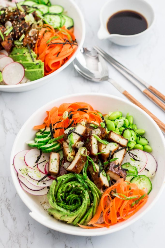 Two hoisin tofu sushi bowls with side of soy sauce in the back ground