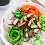 Shot of hoisin tofu sushi bowl, pair of chopsticks, spoon, and soy sauce in the background