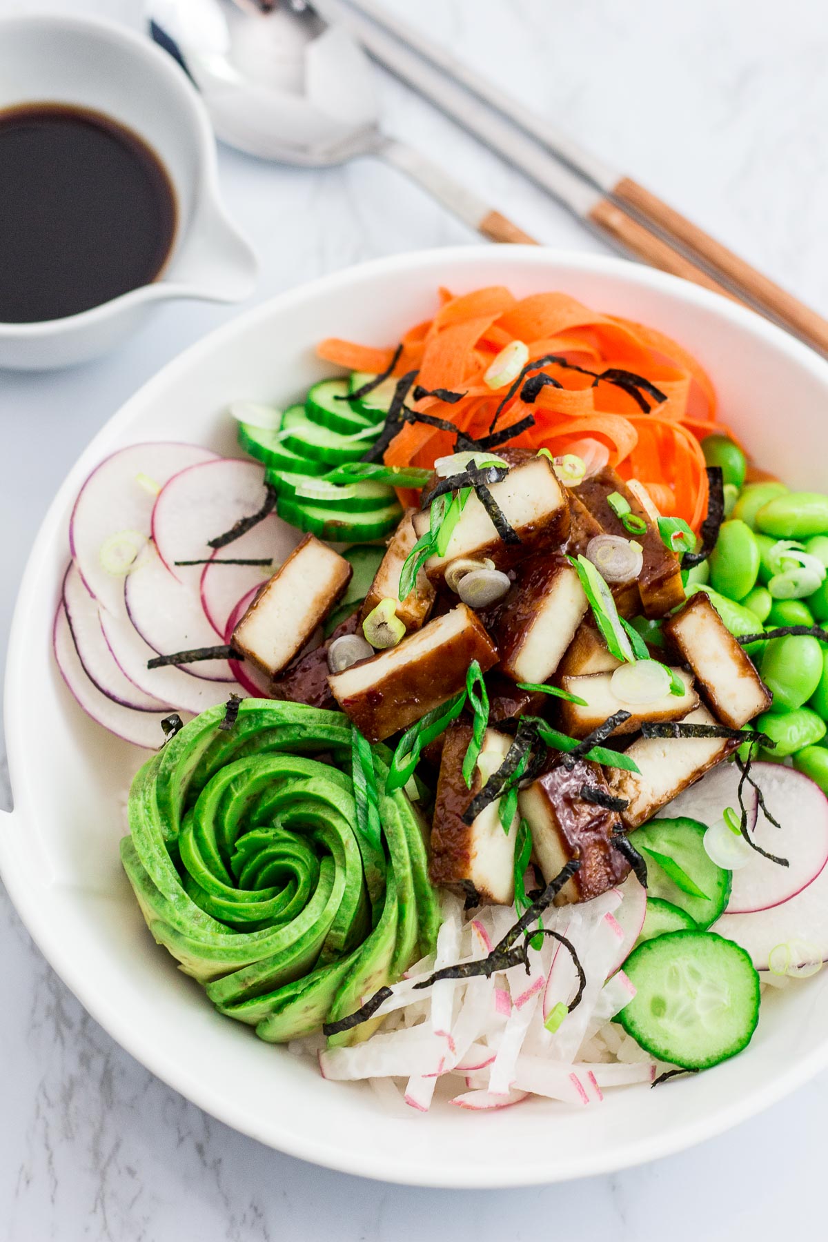 Shot of hoisin tofu sushi bowl, pair of chopsticks, spoon, and soy sauce in the background