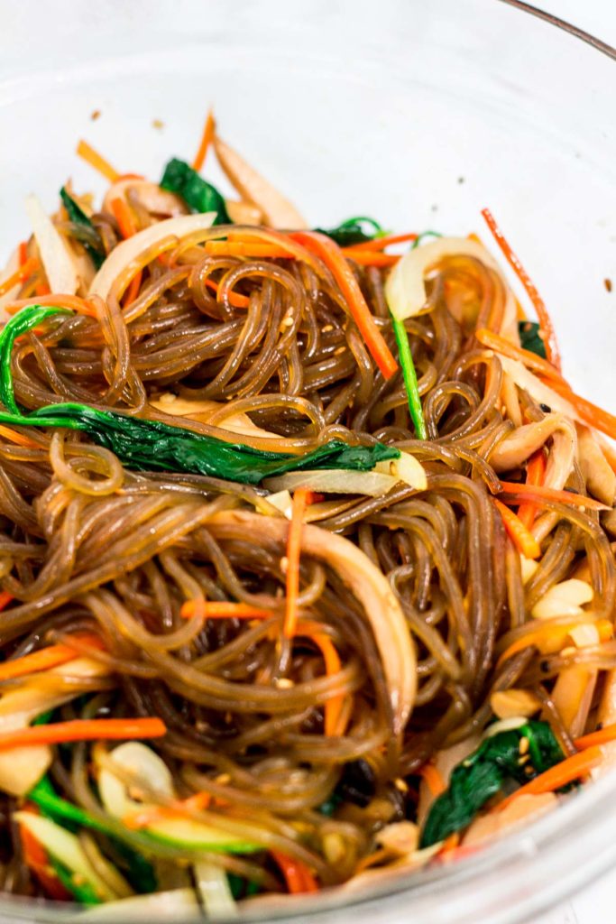 In the process of mixing Korean vegan japchae in a large bowl