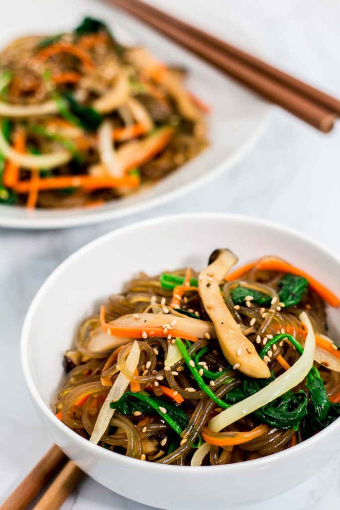 Two bowls of Korean vegan japchae with chopsticks next to them