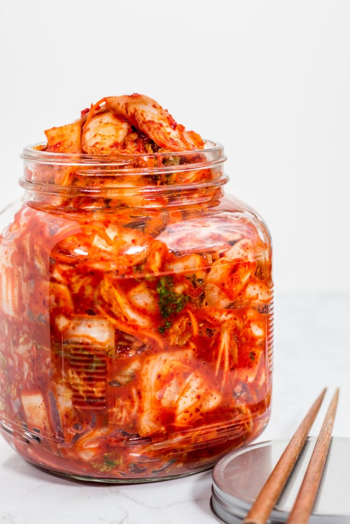 A large glass jar full of freshly made homemade vegan kimchi