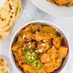 bowl full of Indian style vegan vegetable curry and naan on the side