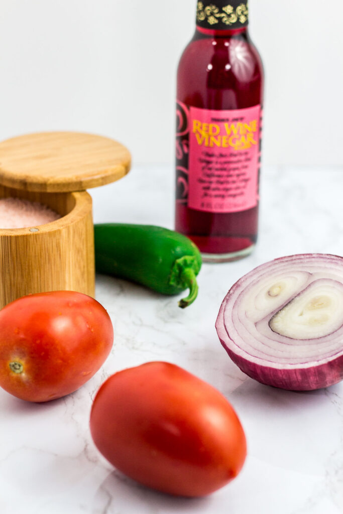 A picture of salt, jalapeno, red onion, roman tomato, and red wine vinegar