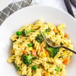 A plate full of no dairy white sauce veggie pasta with gray napkin underneath.