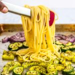 Adding boiled pasta to the sheet pan full of oven roasted summer veggies