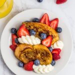 overhead shot of french toast topped with fresh strawberries and blueberries with sweet ricotta cheese