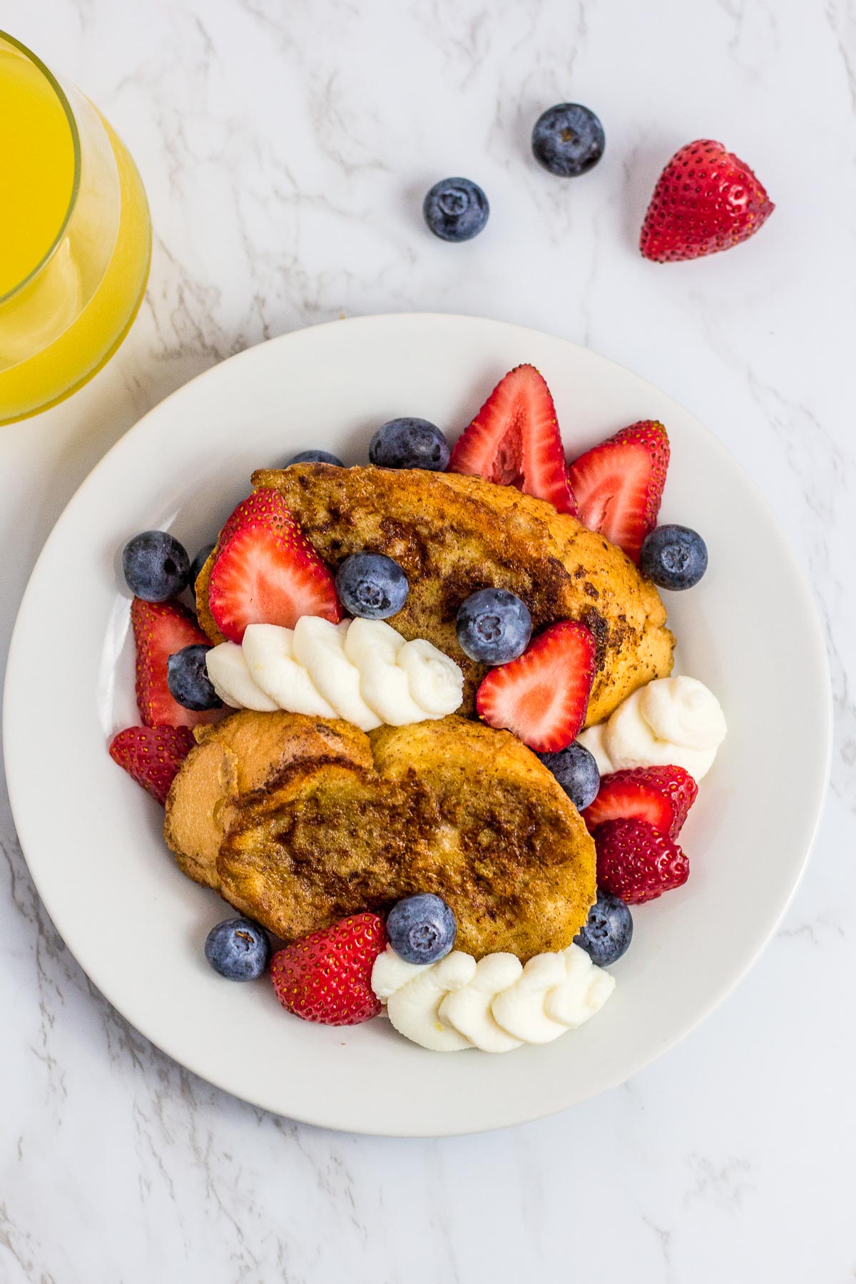 overhead shot of french toast topped with fresh strawberries and blueberries with sweet ricotta cheese