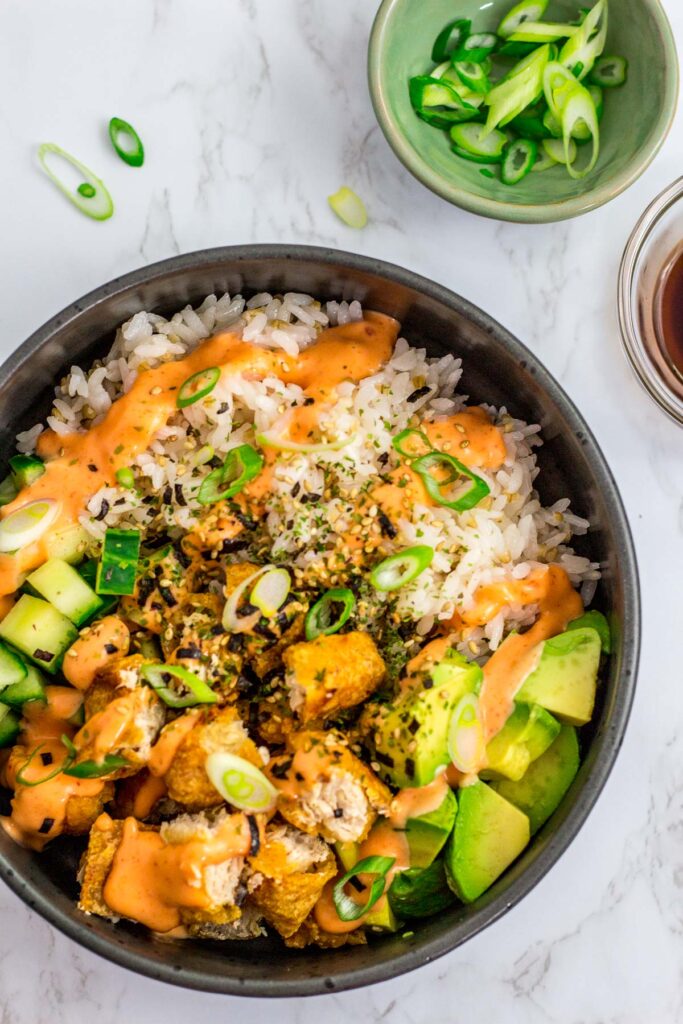 overhead shot of vegan sushi bowl with rice, vegan fish filets, avocado, cucumber