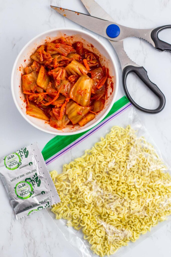 Overhead shot of vegan kimchi and broken ramen in the zip lock bag