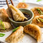 dipping a pan fried homemade Korean veggie tofu mandu/dumpling in a dipping sauce