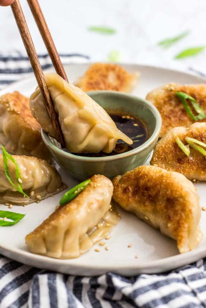 Crispy vegan mandu dipped in soy sauce with scallions