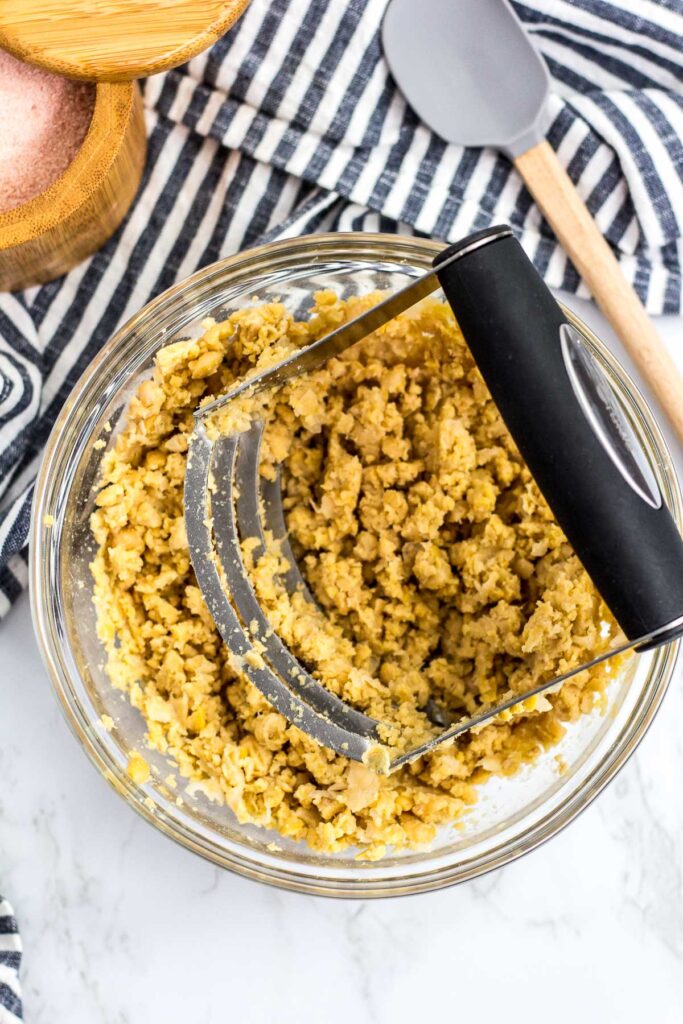 mashed canned chickpea in a bowl using a pastry cutter