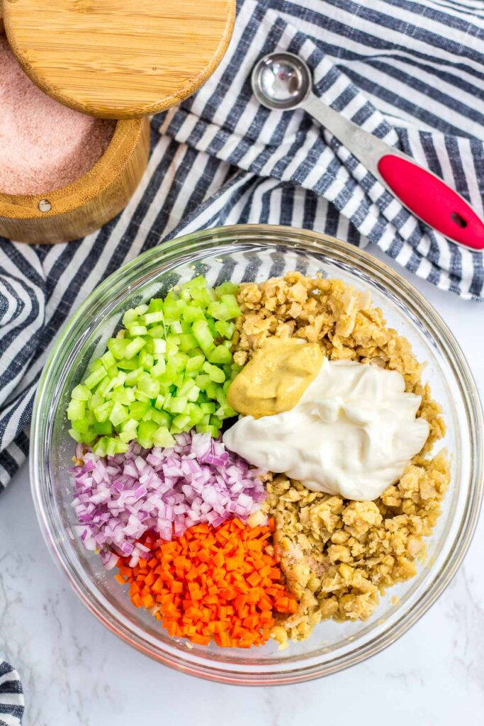 mashed canned chickpea, vegan mayo, dijon mustard, celery, onion, carrot, salt and sugar in a bowl (before mixing)