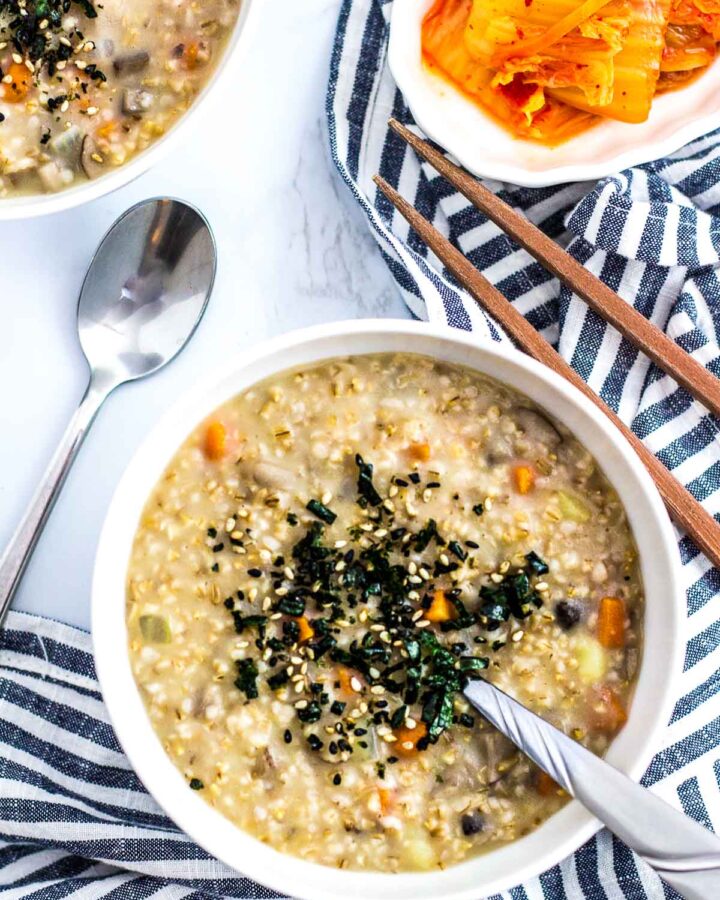 two bowls of vegan savory steel cut oatmeal with side of kimchi