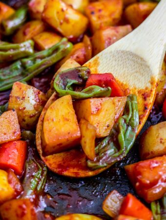 close up photo of spicy braised potatoes and shishito peppers on a wooden spoon