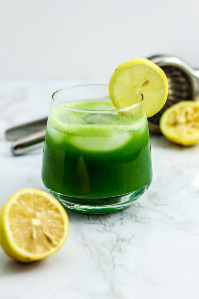 iced matcha lemonade with lemon and citrus squeezer in the background