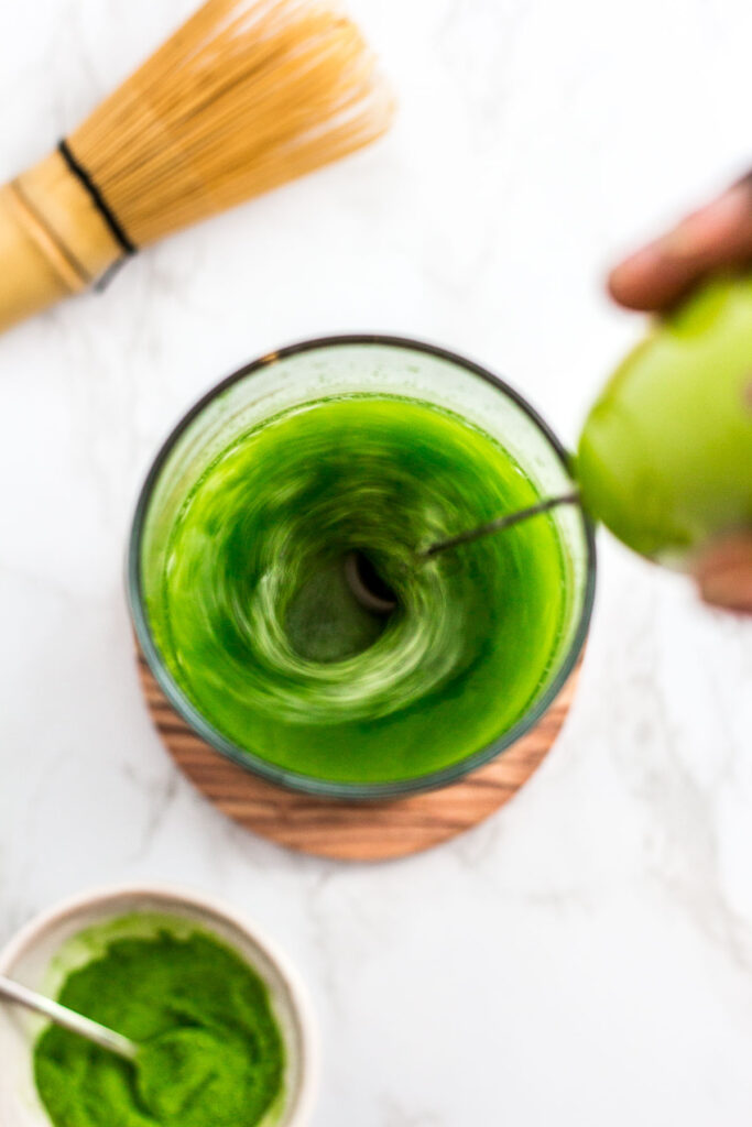 dissolving matcha powder in water with hand held milk frother