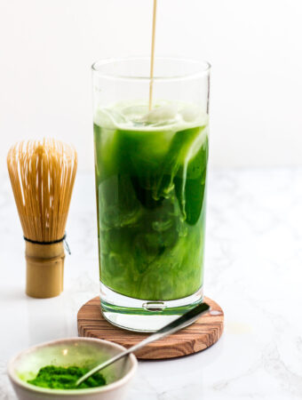 slow pouring of oat milk over iced matcha water