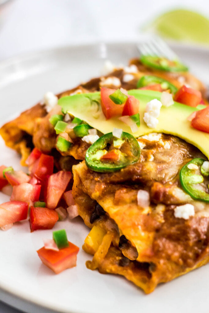 close up shot of two enchiladas cut in half to see the fillings insdie