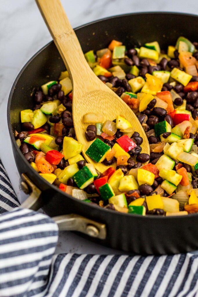 zucchini, yellow squash, tomato, onion, bell pepper and black beans in the pan