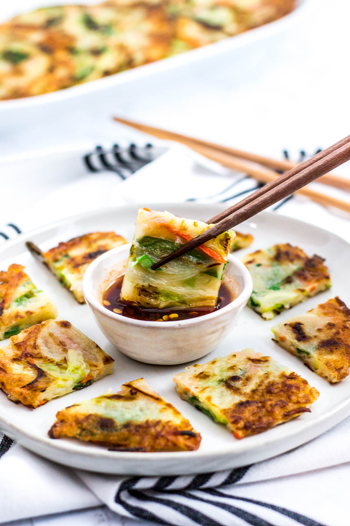 dipping pancake into a sauce with chopsticks