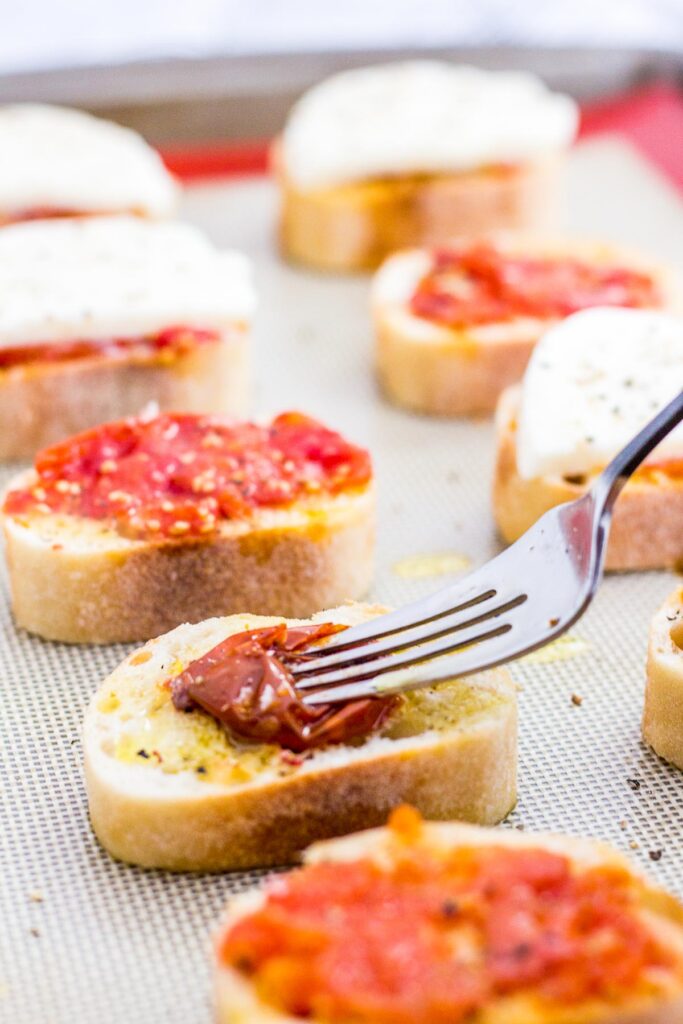 crushing roasted cherry tomato on top of baguette