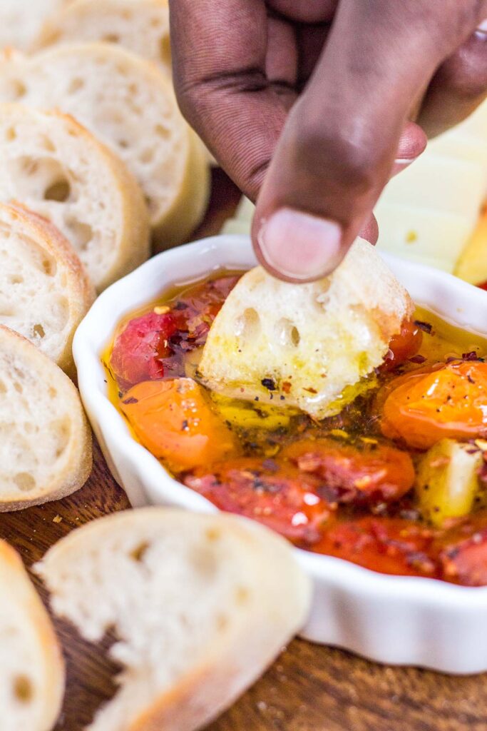 dipping baguette in cherry tomato and garlic oil