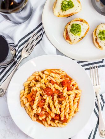 overhead shot of gemelli pasta with roasted cherry tomato sauce in a white bowl