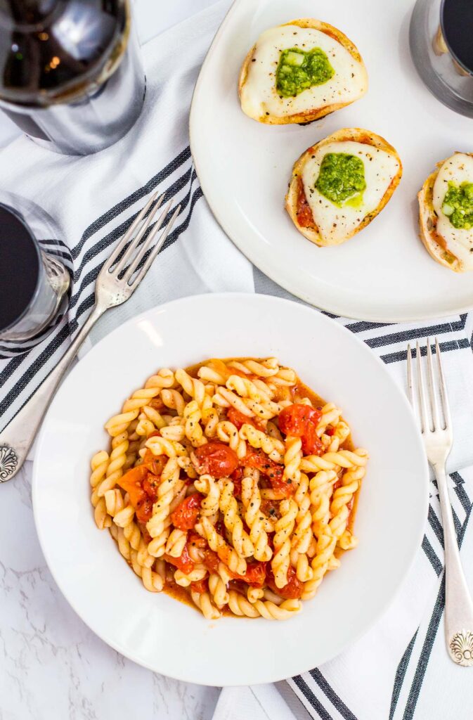 overhead shot of gemelli pasta with roasted cherry tomato sauce in a white bowl