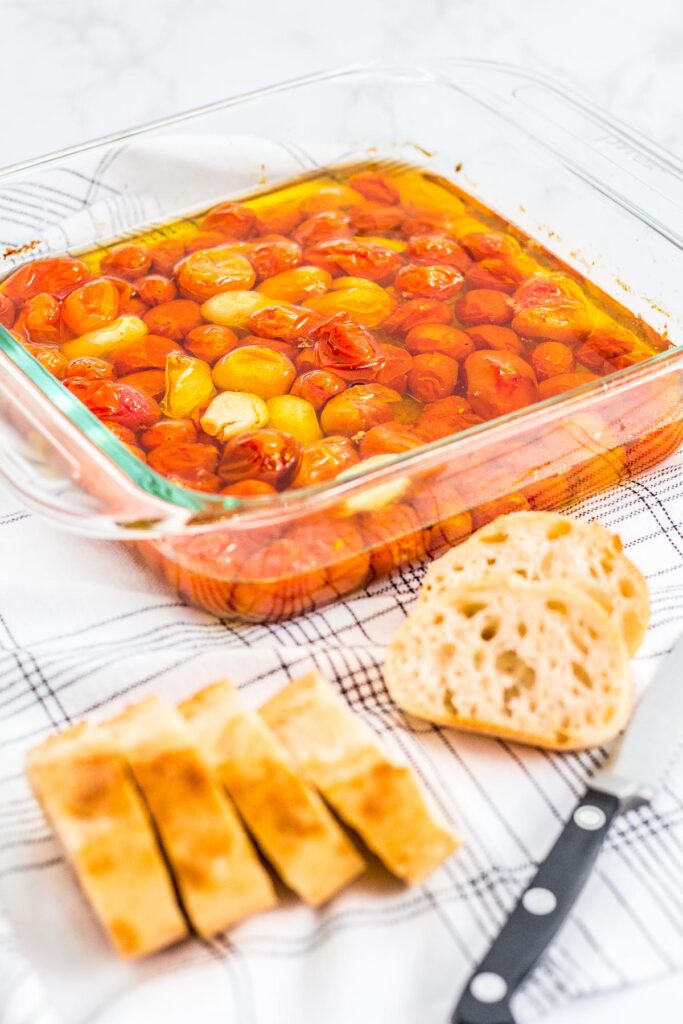 slow roasted cherry tomatoes with some sliced baguette bread in front