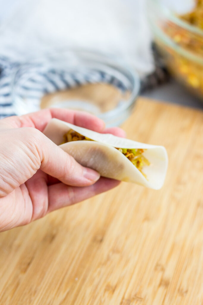 the middle of the filled dumpling wrapper is pinched to close