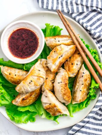 overhead shot of plateful of cooked vegan bulgogi mandu/dumplings with the dipping sauce