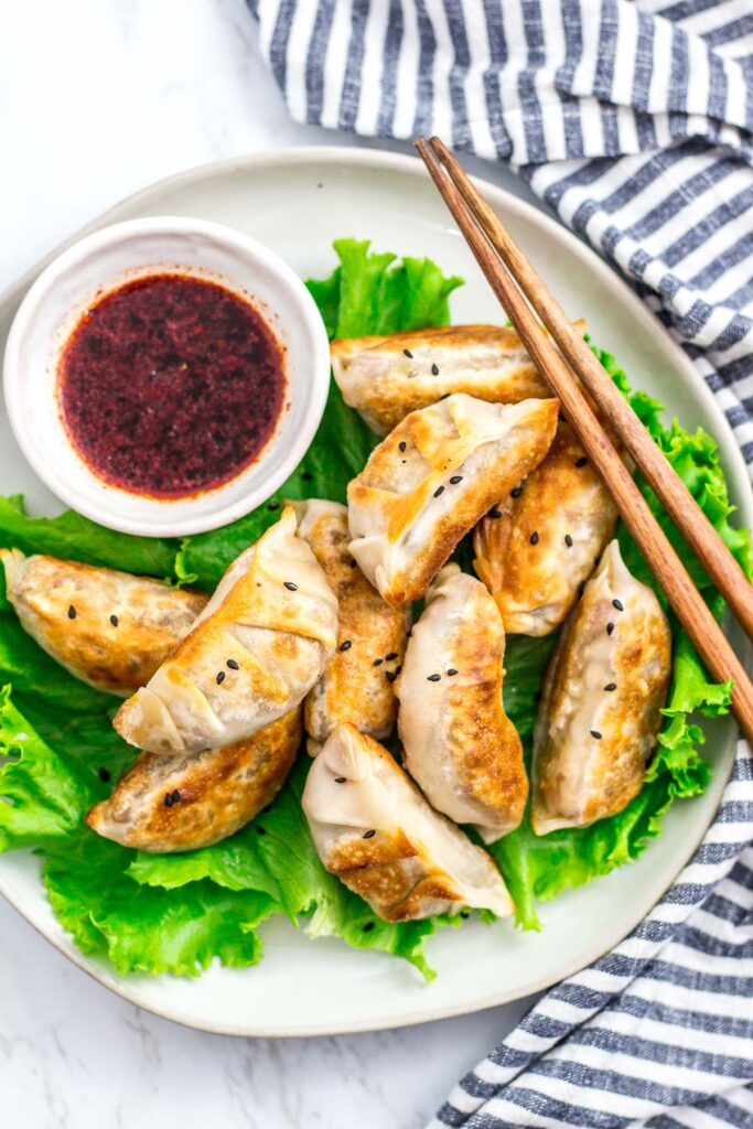 overhead shot of plateful of cooked vegan bulgogi mandu/dumplings with the dipping sauce