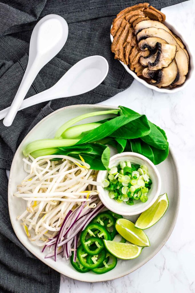 baby bok choy, bean sprouts, jalapeno, green onion, onion, lime wedges, seitan, and mushroom for pho toppings