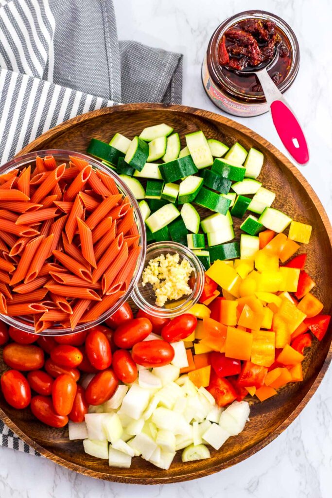 vegetables, uncooked red lentil pasta, and sun-dried tomato in olive oil