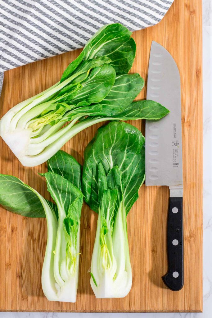 Bok choy cut in half and cut in half length wise again on the cutting board